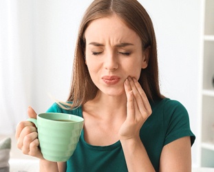 Woman experiencing tooth pain after sipping hot drink
