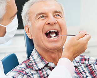 Older male patient examined in dental chair