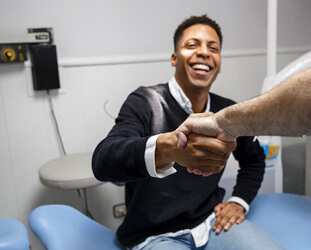 smiling patient shaking dentist hand